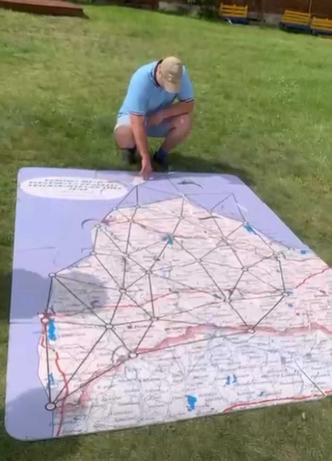 Uz attēla cilvēks skatās lielo karti, kas ir izklāsta uz zemes